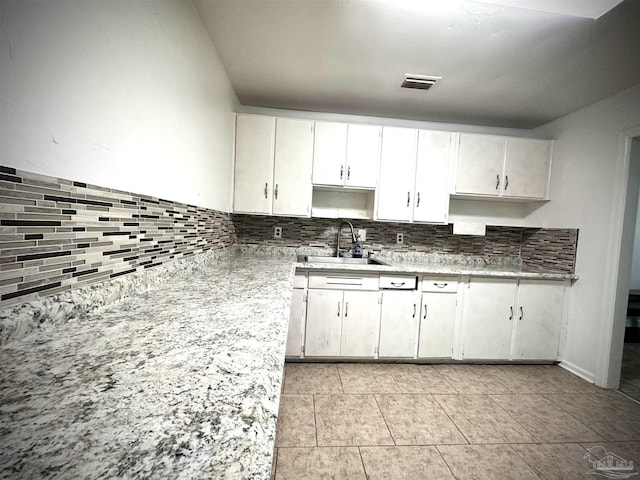 kitchen with decorative backsplash, white cabinetry, and sink