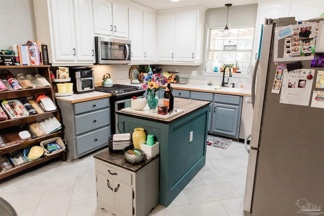 kitchen featuring stainless steel appliances, decorative light fixtures, a kitchen island, and white cabinets