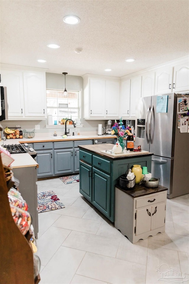 kitchen with white cabinetry, stainless steel fridge with ice dispenser, a textured ceiling, and pendant lighting