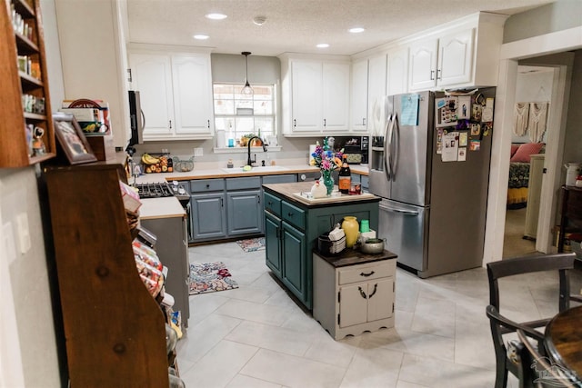 kitchen featuring sink, appliances with stainless steel finishes, white cabinetry, hanging light fixtures, and a kitchen island