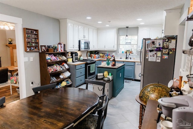 kitchen with white cabinetry, appliances with stainless steel finishes, blue cabinetry, and a center island