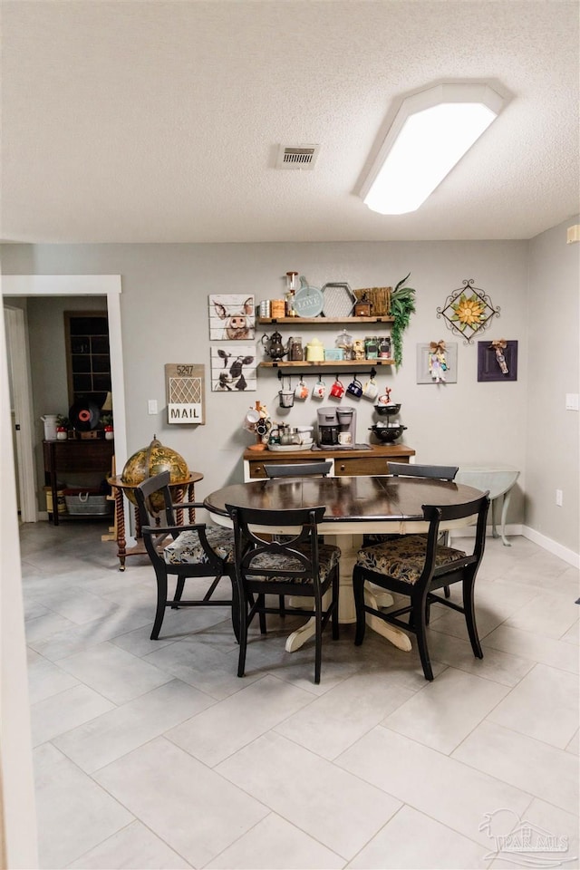 tiled dining space with a textured ceiling