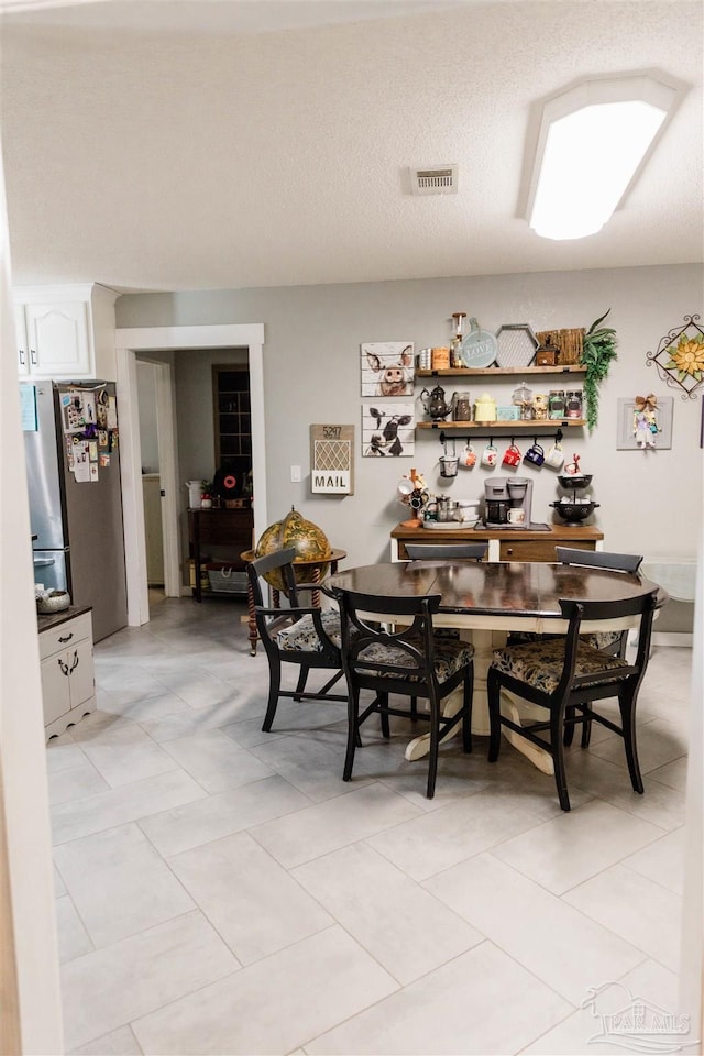 tiled dining area featuring a textured ceiling