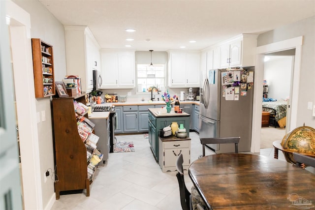 kitchen featuring sink, hanging light fixtures, stainless steel appliances, a center island, and white cabinets