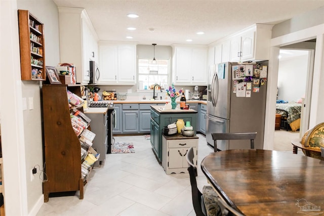 kitchen featuring stainless steel appliances, hanging light fixtures, sink, and white cabinets