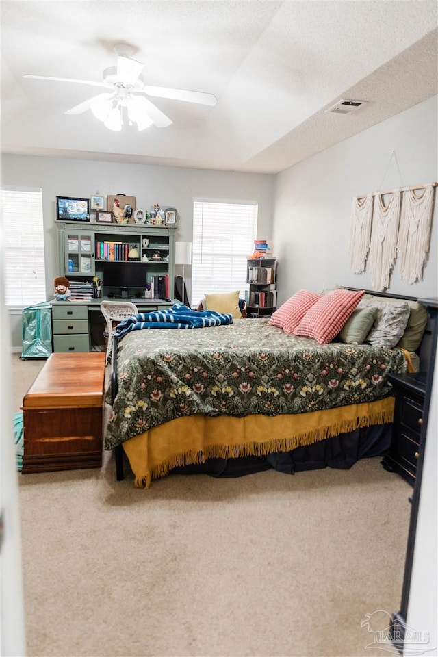 bedroom with ceiling fan, carpet, and a textured ceiling