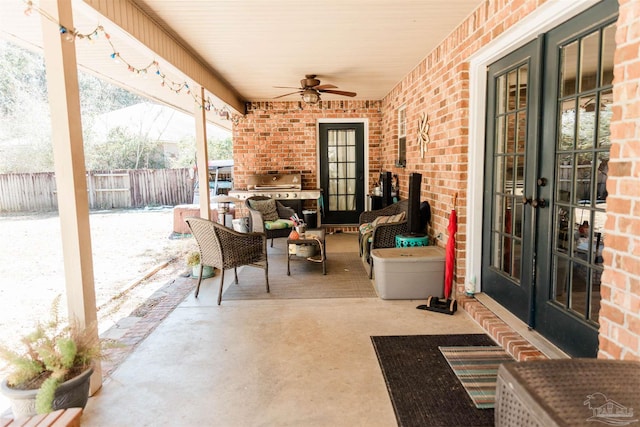 snow covered patio featuring french doors, ceiling fan, and an outdoor living space