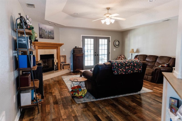 living room with french doors, a fireplace, dark hardwood / wood-style flooring, and a raised ceiling