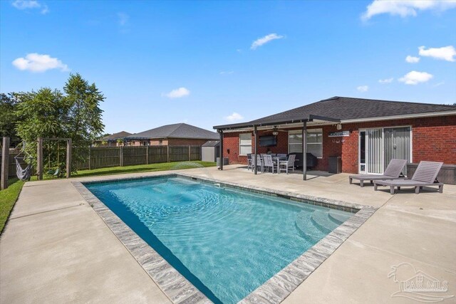 view of pool with area for grilling and a patio