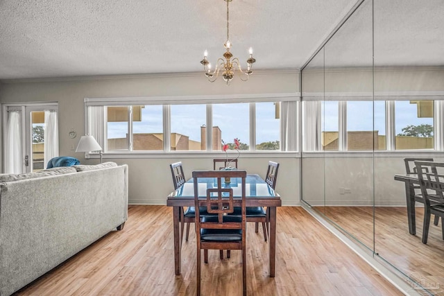 dining space featuring a chandelier, a textured ceiling, baseboards, and wood finished floors