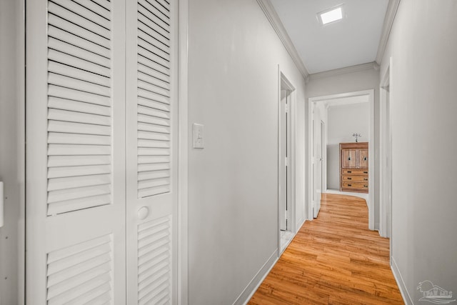 hall with ornamental molding, light wood-style flooring, and baseboards