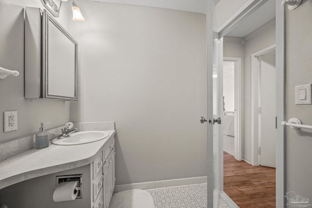 bathroom with crown molding, vanity, baseboards, and wood finished floors