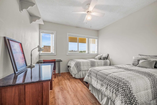 bedroom with a textured ceiling, baseboards, a ceiling fan, and light wood-style floors