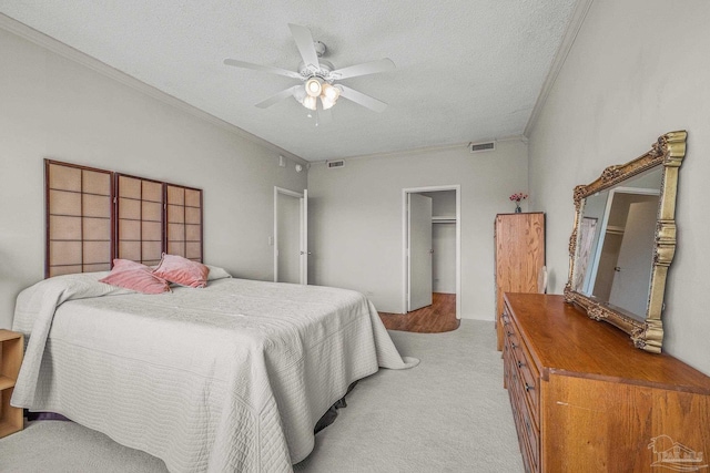 bedroom featuring visible vents, a ceiling fan, light colored carpet, crown molding, and a textured ceiling