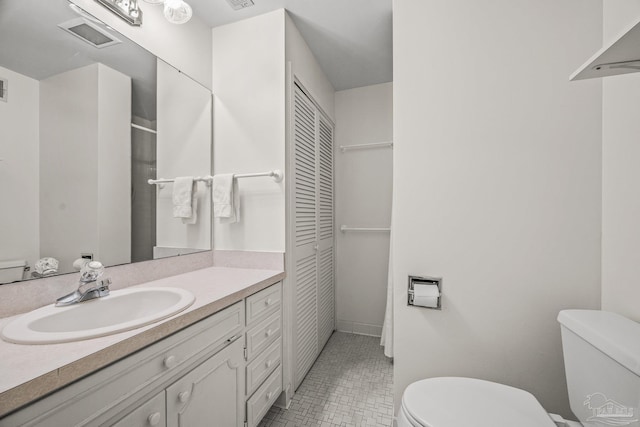 bathroom featuring visible vents, a closet, vanity, and toilet