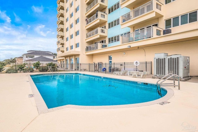 view of pool with cooling unit and fence