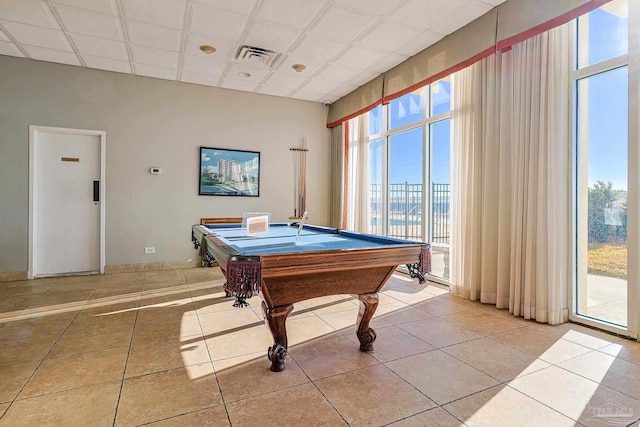 recreation room featuring a healthy amount of sunlight, visible vents, a drop ceiling, and tile patterned floors