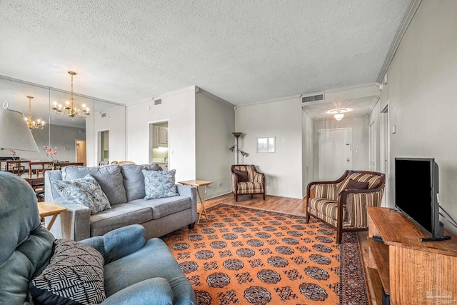 living area featuring crown molding, a notable chandelier, visible vents, a textured ceiling, and wood finished floors