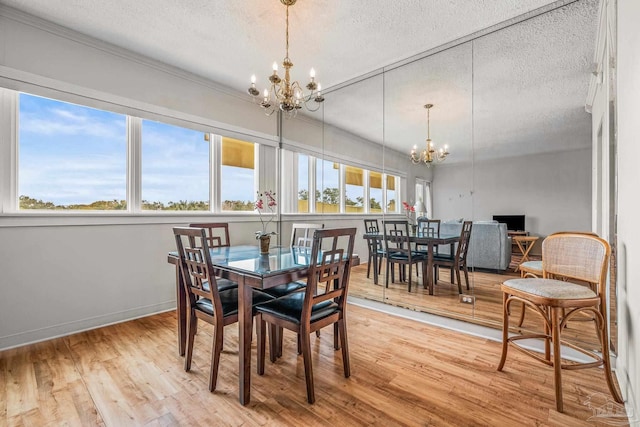 dining space featuring light wood-style flooring, a textured ceiling, and an inviting chandelier