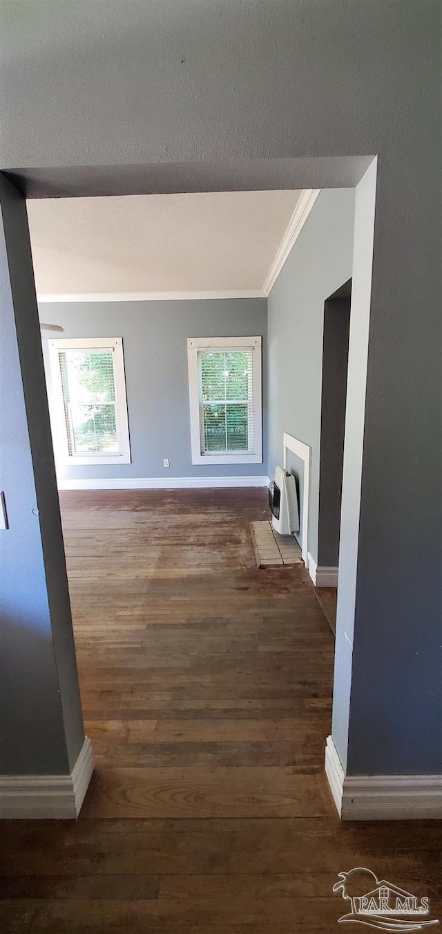 corridor with dark wood-type flooring, ornamental molding, a healthy amount of sunlight, and heating unit