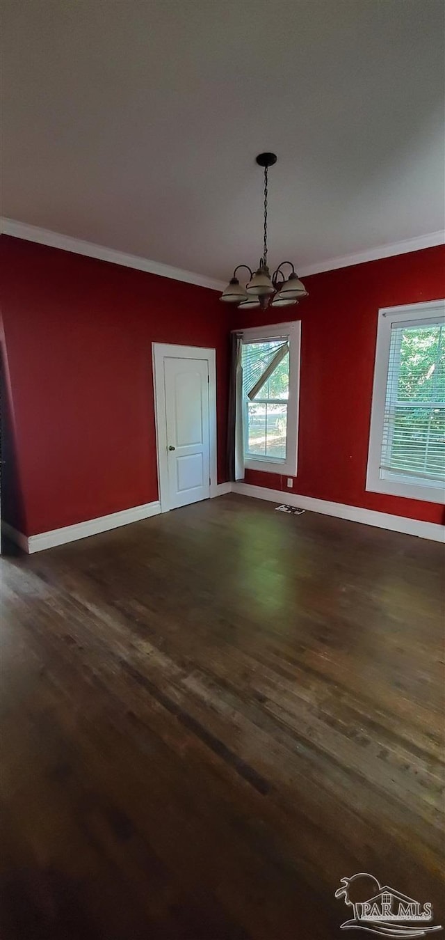 unfurnished dining area featuring dark hardwood / wood-style flooring, ornamental molding, and a chandelier