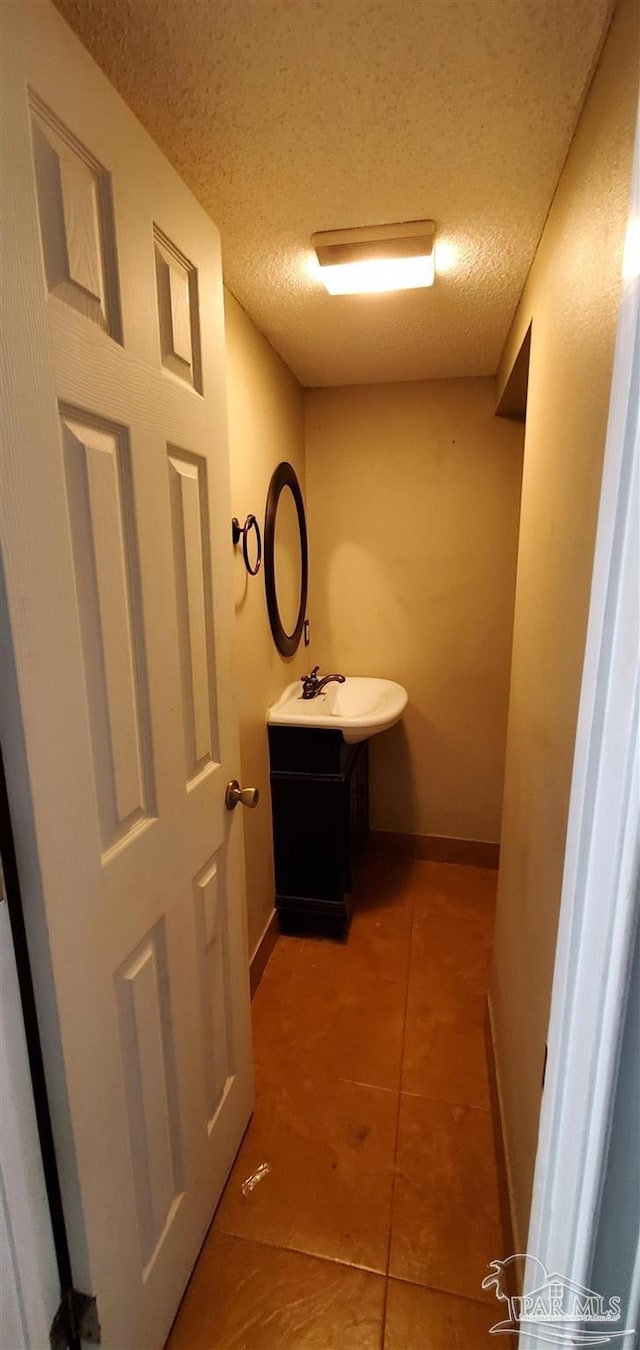 bathroom with a textured ceiling, tile patterned floors, and vanity