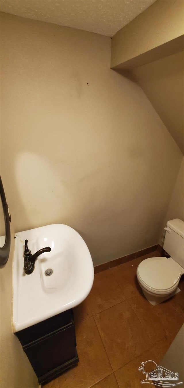 bathroom with a textured ceiling, tile patterned floors, and toilet