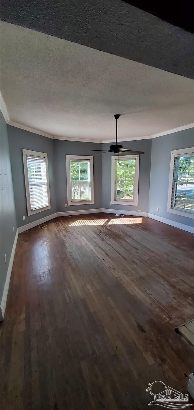 empty room with dark hardwood / wood-style flooring, a textured ceiling, ceiling fan, and crown molding