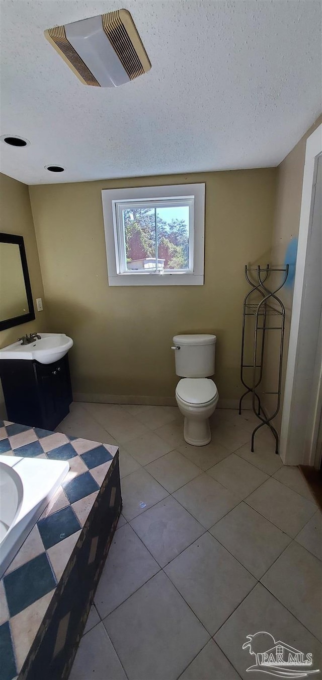 bathroom featuring toilet, tile patterned floors, vanity, and a textured ceiling