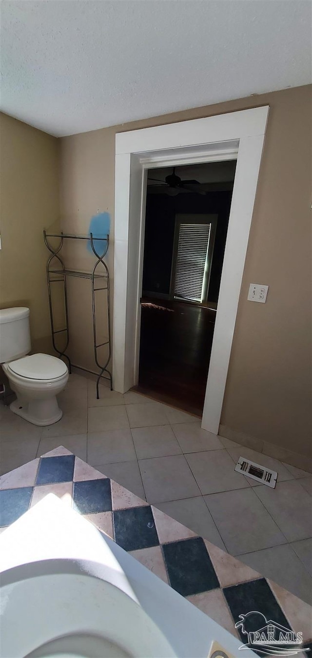 bathroom featuring toilet, a textured ceiling, and tile patterned floors