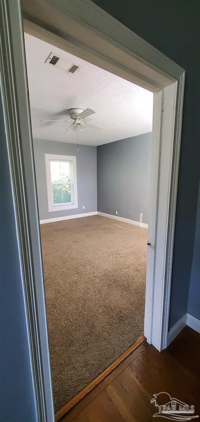 unfurnished room with a textured ceiling, ceiling fan, and dark hardwood / wood-style flooring