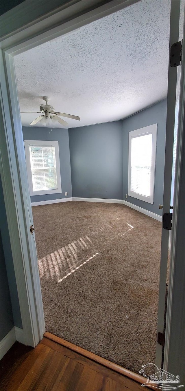 spare room featuring a textured ceiling, ceiling fan, and dark hardwood / wood-style flooring