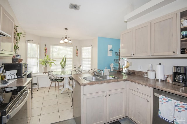 kitchen with light tile patterned flooring, appliances with stainless steel finishes, a sink, a peninsula, and visible vents