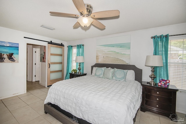 bedroom featuring light tile patterned floors, ceiling fan, a barn door, and visible vents