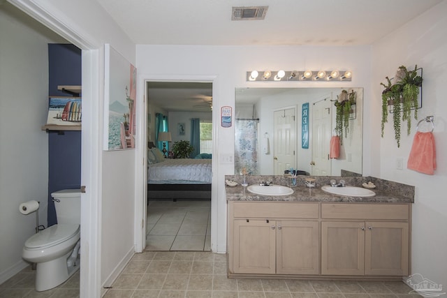 ensuite bathroom featuring double vanity, toilet, visible vents, and a sink
