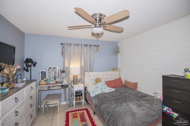 bedroom featuring light tile patterned floors, ceiling fan, and wooden walls