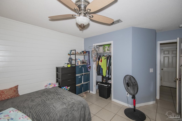 bedroom featuring a closet, visible vents, baseboards, ceiling fan, and light tile patterned floors