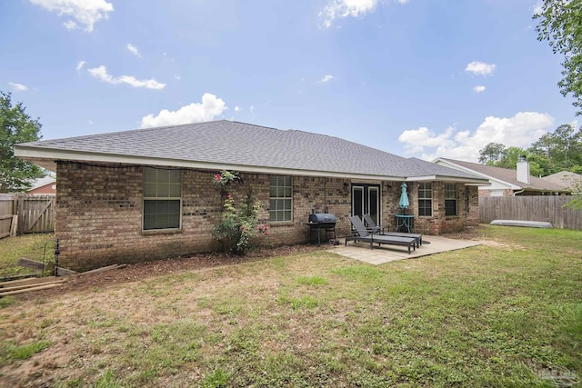 rear view of property featuring a patio, a fenced backyard, roof with shingles, and brick siding