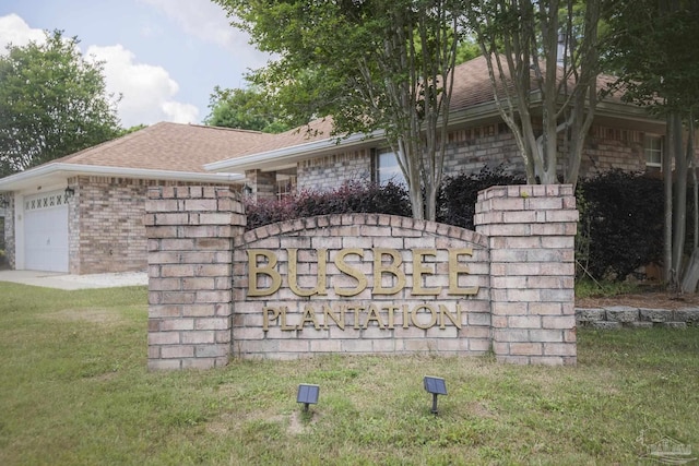 community sign with a lawn and an attached garage