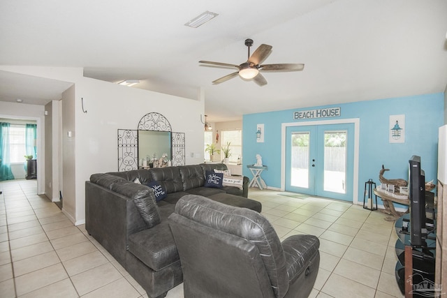 living area with light tile patterned flooring, a healthy amount of sunlight, french doors, a ceiling fan, and vaulted ceiling