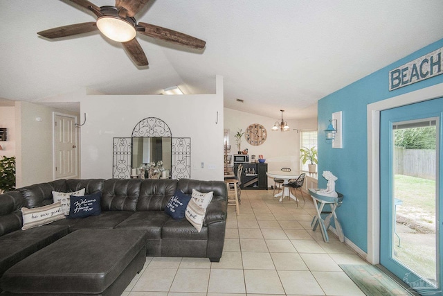 living room featuring vaulted ceiling, light tile patterned floors, and ceiling fan with notable chandelier