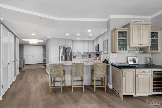 kitchen with wine cooler, sink, light hardwood / wood-style flooring, ornamental molding, and appliances with stainless steel finishes