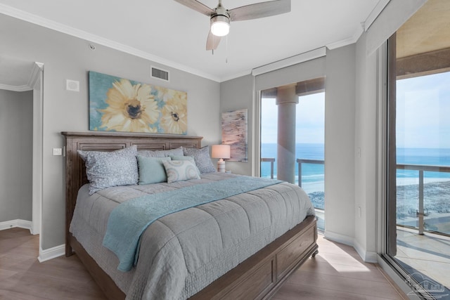 bedroom featuring multiple windows, access to exterior, crown molding, and a water view