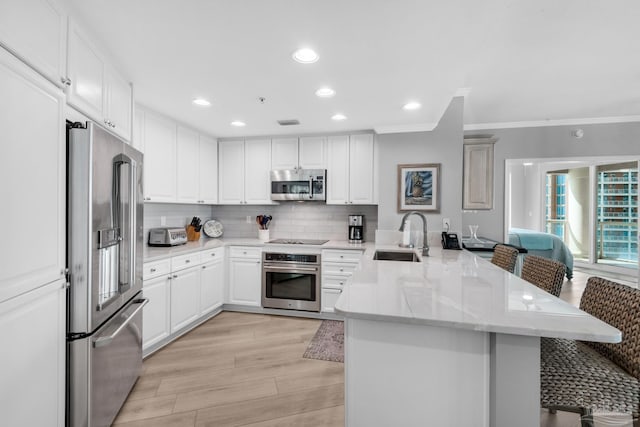 kitchen featuring stainless steel appliances, a breakfast bar, sink, and kitchen peninsula