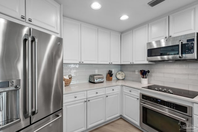 kitchen with white cabinetry, light stone countertops, backsplash, and stainless steel appliances