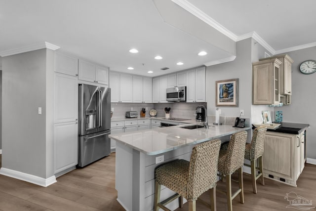 kitchen with appliances with stainless steel finishes, sink, light hardwood / wood-style floors, and kitchen peninsula