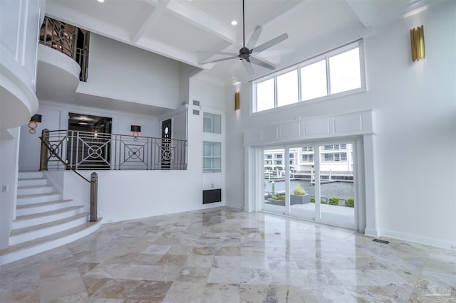 unfurnished living room with beam ceiling, ceiling fan, ornamental molding, a high ceiling, and coffered ceiling