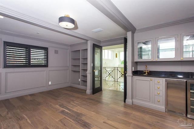 bar with hardwood / wood-style floors, white cabinets, crown molding, and stainless steel refrigerator