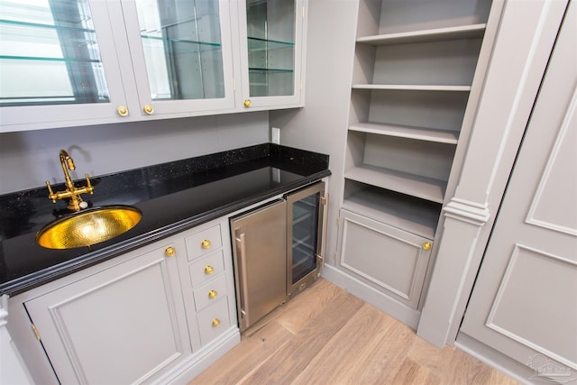 bar featuring sink, white cabinets, and light hardwood / wood-style flooring