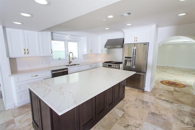 kitchen with tasteful backsplash, appliances with stainless steel finishes, sink, wall chimney exhaust hood, and a center island